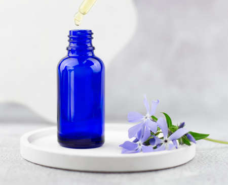 Serum drips from a glass pipette into a bottle. Natural skin care concept. Essential oil with cherry tree extract. Natural herbal products.の写真素材