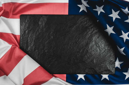 Black stone plaque on the American flag with place for text.の写真素材