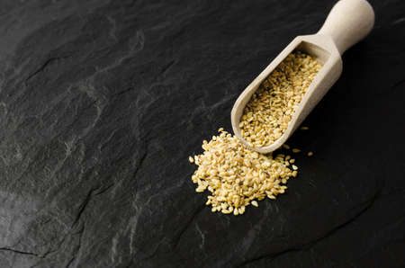 Flax seeds in a wooden scoop on a black stone background with place for textの写真素材