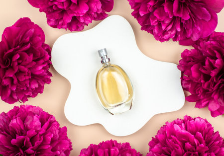 Women's perfume on a white plaster podium with peony flowers, top view.の写真素材