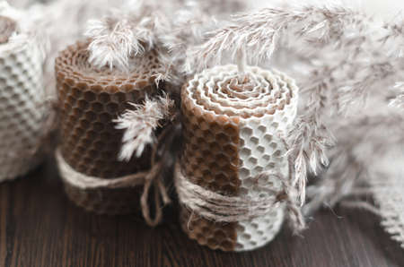 Decorative candles for home decoration. Handmade wax candles on a dark wooden background with sprigs...
