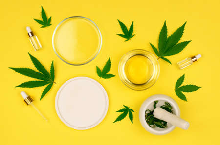 Natural hemp oil. Composition of cannabis oil bottles and hemp leaves on yellow background, mock up, flat lay.の写真素材