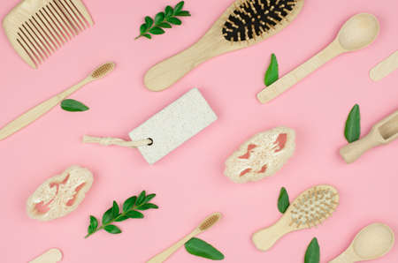 Zero waste. Wooden accessories for personal care and daily life with green leaves on a pink...
