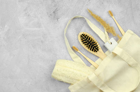 Eco-friendly personal care products in a linen bag. Bamboo toothbrushes, wooden comb, pumice stone and loofah washcloth on concrete backgroundの写真素材