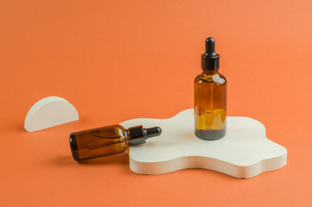 Cosmetics, body care. Flavored oil bottle on white geometric podium. Essential oil or serum in a brown bottle with a dropper.の写真素材