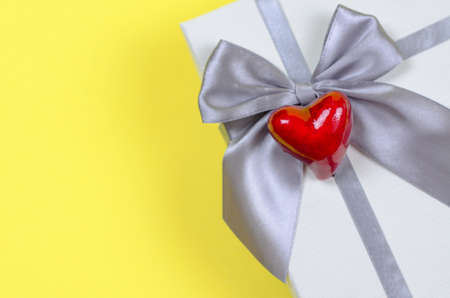 Gift box on a yellow background close-up. Red heart on a gift box, copy spaceの写真素材