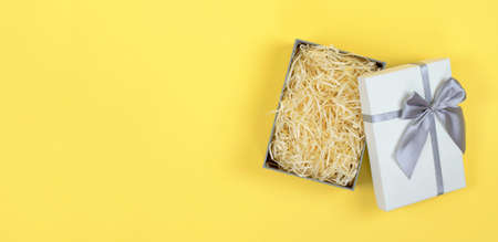 Gift box with filler on a yellow background for product advertising. Open gift box mockup, flat layの写真素材
