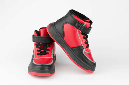 Children's shoes on a white background. A pair of children's sports shoes on a white background. Stylish red-black sneakersの写真素材