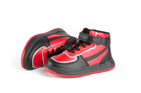 A pair of children's sports shoes on a white background. Children's shoes on a white background. Stylish red and black sneakersの写真素材