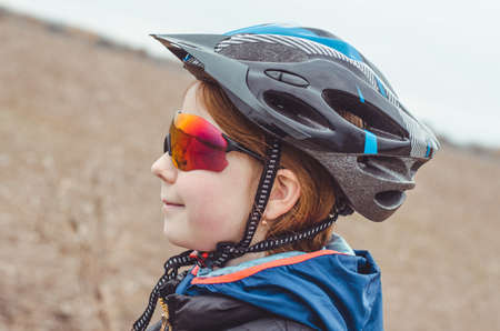 Side view of a girl in a protective bicycle helmet and bicycle goggles. Bicycle travel, healthy lifestyleの写真素材