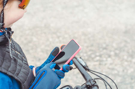 Cyclist hands in gloves hold a smartphone, mock up. Traveler looking for directions using maps in smartphoneの写真素材