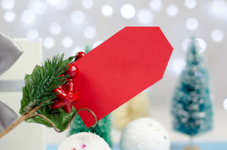 Blank red tag on a Christmas background, close-up. Christmas and New Year discounts and sales.