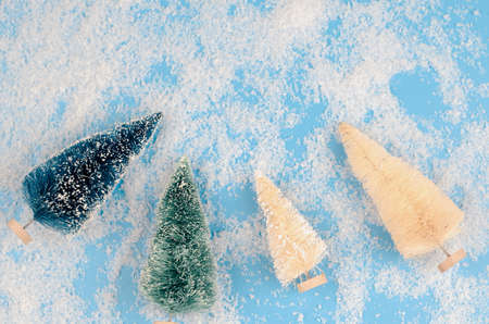 Christmas trees of different colors and sizes on a blue snowy background. Christmas background with...