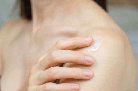 Close-up of a woman applying moisturizer to her shoulderの写真素材