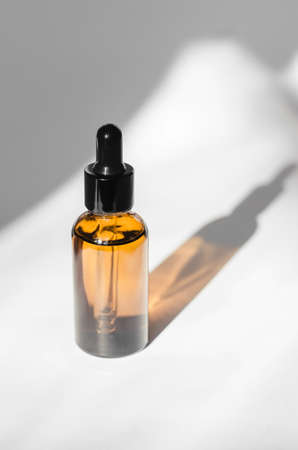 Essential oil or serum bottle on white background with shadows. Body care cosmeticsの写真素材