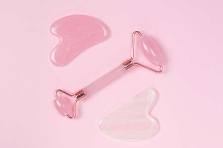 Jade facial massager and gua sha massage scraper on pink background. Facial skin care productsの写真素材