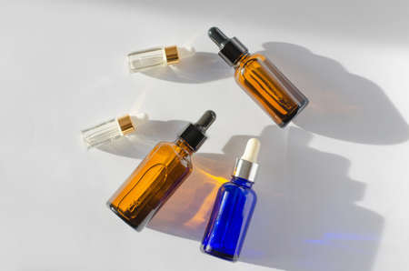 Bottles with essential oils of different colors and sizes on a white background with shadowsの写真素材