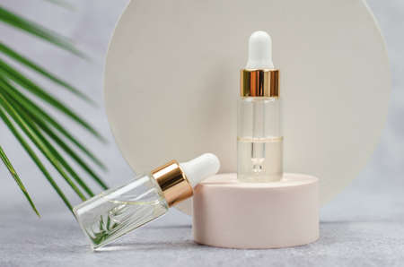 Essential oil bottle on a round podium with palm leafの写真素材