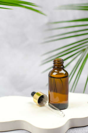 Natural essential oil on a white podium in an open bottle. Serum in a glass bottle with a pipette.の写真素材