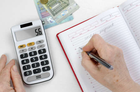 The pensioner calculates utility costs. Elderly woman hands are counting finances on a calculator