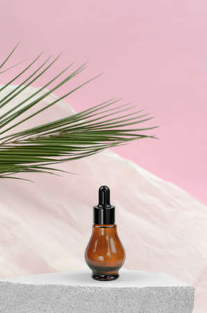 Natural essential oil or serum in a bottle with a pipette on a gray podium. Natural hyaluronic serum in bottles with a pipetteの写真素材