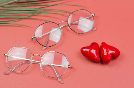 Glasses for vision on a red background with hearts. Advertising for an optics store. Poor vision conceptの写真素材