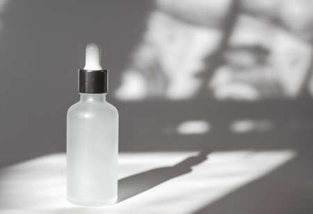 White cosmetic bottle with essential oil on a white background with shadows. Cosmetic branding mockup. skincare conceptの写真素材