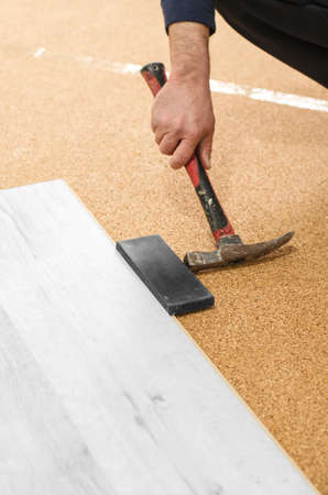 Unrecognizable man laying laminate flooring. Repair in the apartment. Professional laying of a floor covering - a laminate. Laminate installation processの写真素材