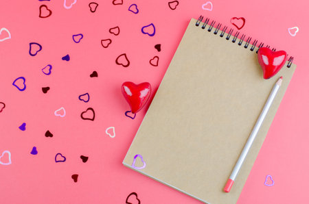 Blank notebook with kraft paper on a pink background with hearts. The concept of Valentine's day,...