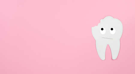 The concept of dental care, caries, copy space. A white tooth looks at the place of caries on a pink background.の写真素材