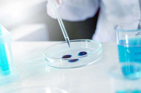 Close-up of a scientist's hand with a laboratory pipette. Equipment for chemical experiments....