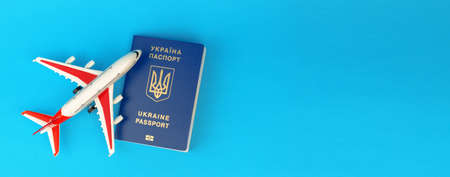 Passport of a citizen of Ukraine and a toy plane on a blue background, a banner. Inscription in Ukrainian Ukraine Passport.の写真素材