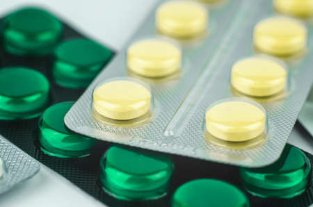 Packs of pills close-up. Yellow and green pills in blister packsの写真素材