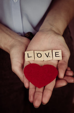Red heart and the inscription Love in a female palm.