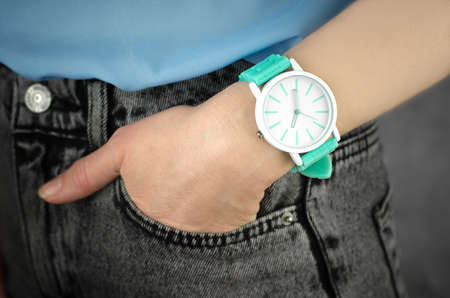 Stylish green wrist watch on a female hand, close-up