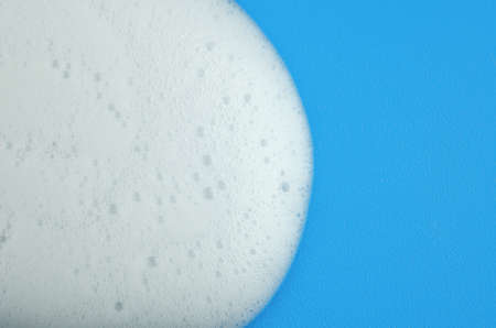 Macro photo of white shampoo foam on blue backgroundの写真素材