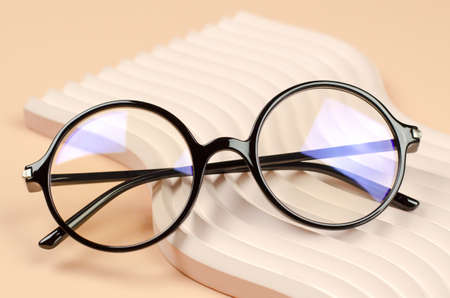 Stylish round glasses for vision on a wavy beige podiumの写真素材