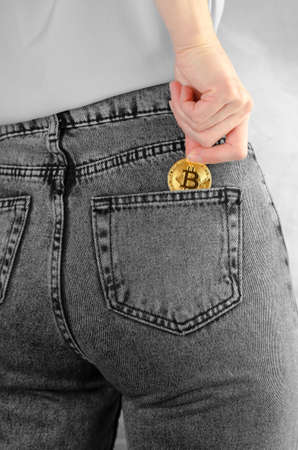 A woman's hand puts Ethereum in the back pocket of her jeans. Ethereum in a female hand....