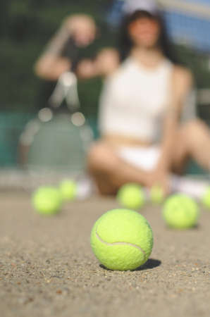 A close-up tennis ball lies on the court against the background of an unrecognizable tennis player. selective focus.の写真素材