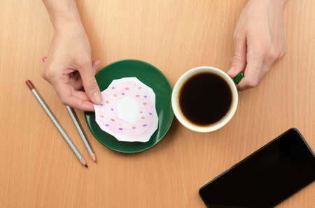 A cup of coffee and a painted donut on a saucer. The concept of lack of food or moneyの写真素材