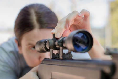A female sniper adjusts an optical sight while looking into itの写真素材