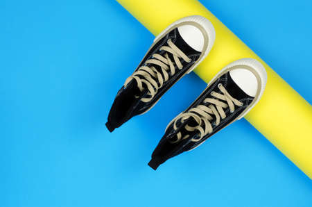 Stylish black sneakers for teenagers on a yellow and blue background. Sneakers on a colored backgroundの写真素材