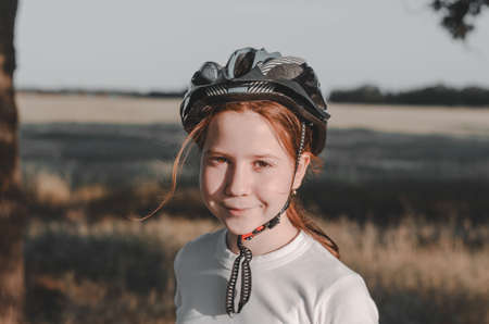 Red-haired 11-year-old girl in a bicycle helmet on a walk in the countryside