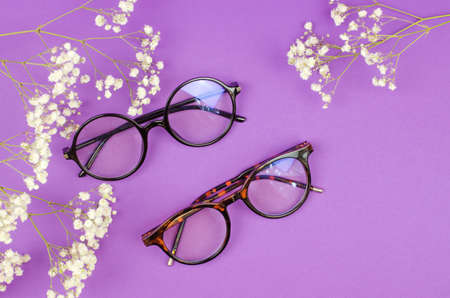 Stylish women's glasses on a purple background with sprigs of gypsophilaの写真素材