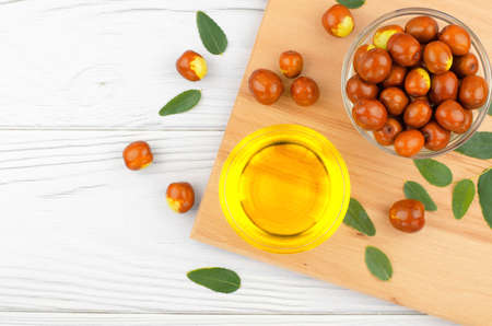 Fresh ripe jojoba fruit and jojoba oil in bowl on wooden tableの写真素材