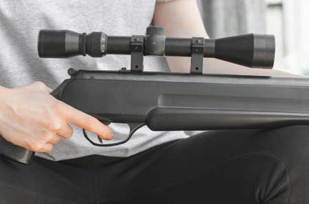 A young woman with a gun in her hands. A woman is holding a large sniper rifle, close-up. Air rifle...