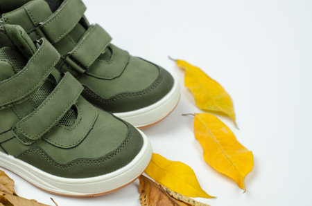 Stylish demi-season men's shoes on a white background with yellow autumn leaves. Green men's bootsの写真素材