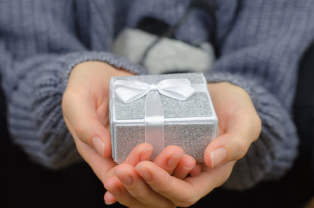 Gift box in female hands, close-up. Woman with white small gift boxの写真素材