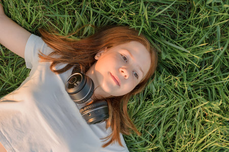 Portrait of a 12-year-old red-haired teenage girl who lies on the grassの写真素材
