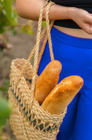 Two baguettes in a wicker bag made of natural materials, close-up, selective focus. Two fresh crispy baguettesの写真素材